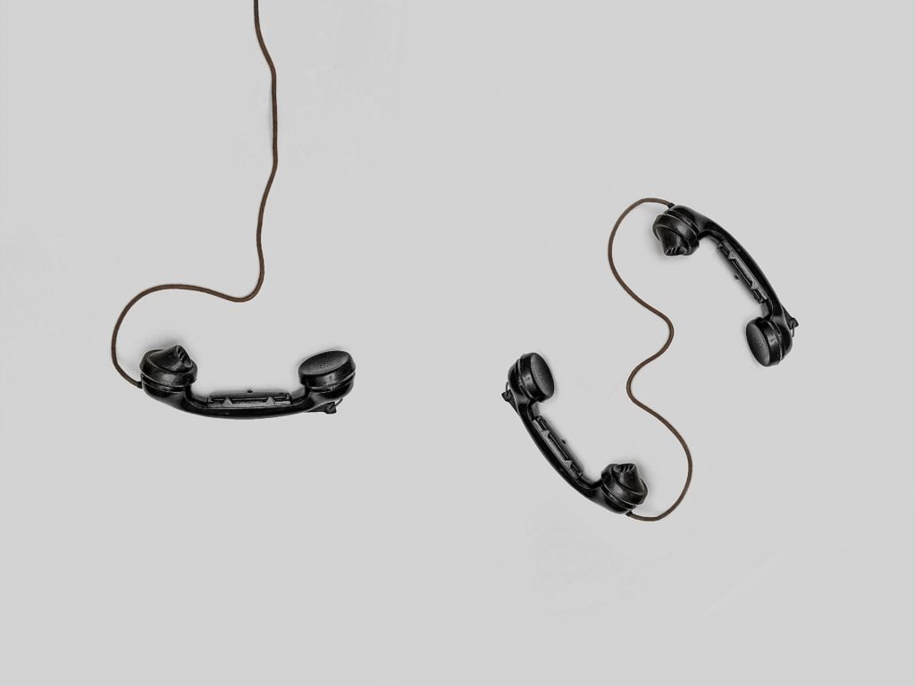 A picture of two phones connecting by a wire as this article is about the secure encryption method known as public-key cryptography, or asymmetric encryption.