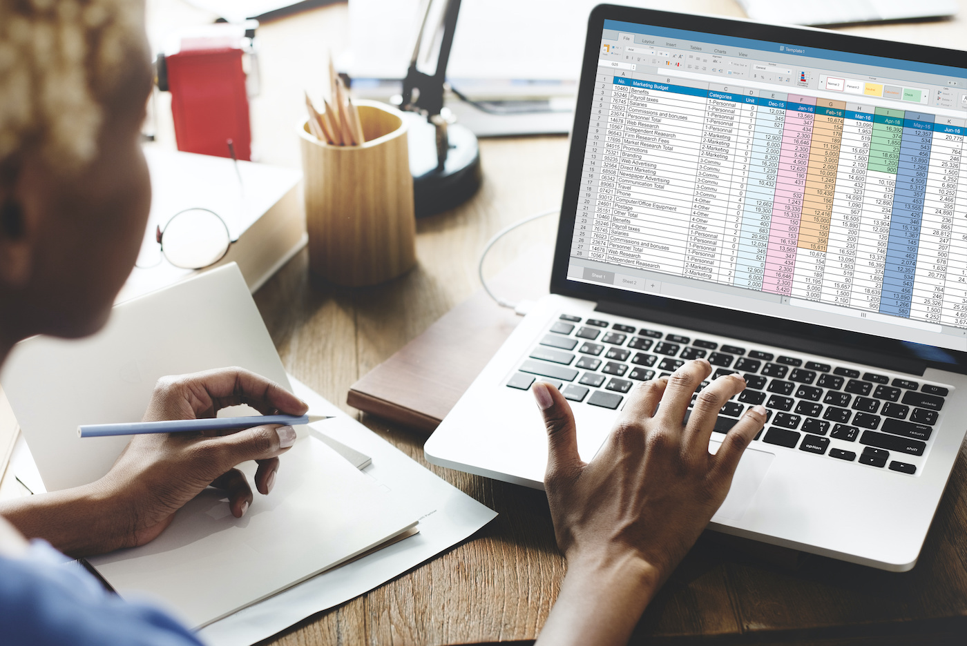 Image of business person using fill handle in Microsoft Excel on a laptop.
