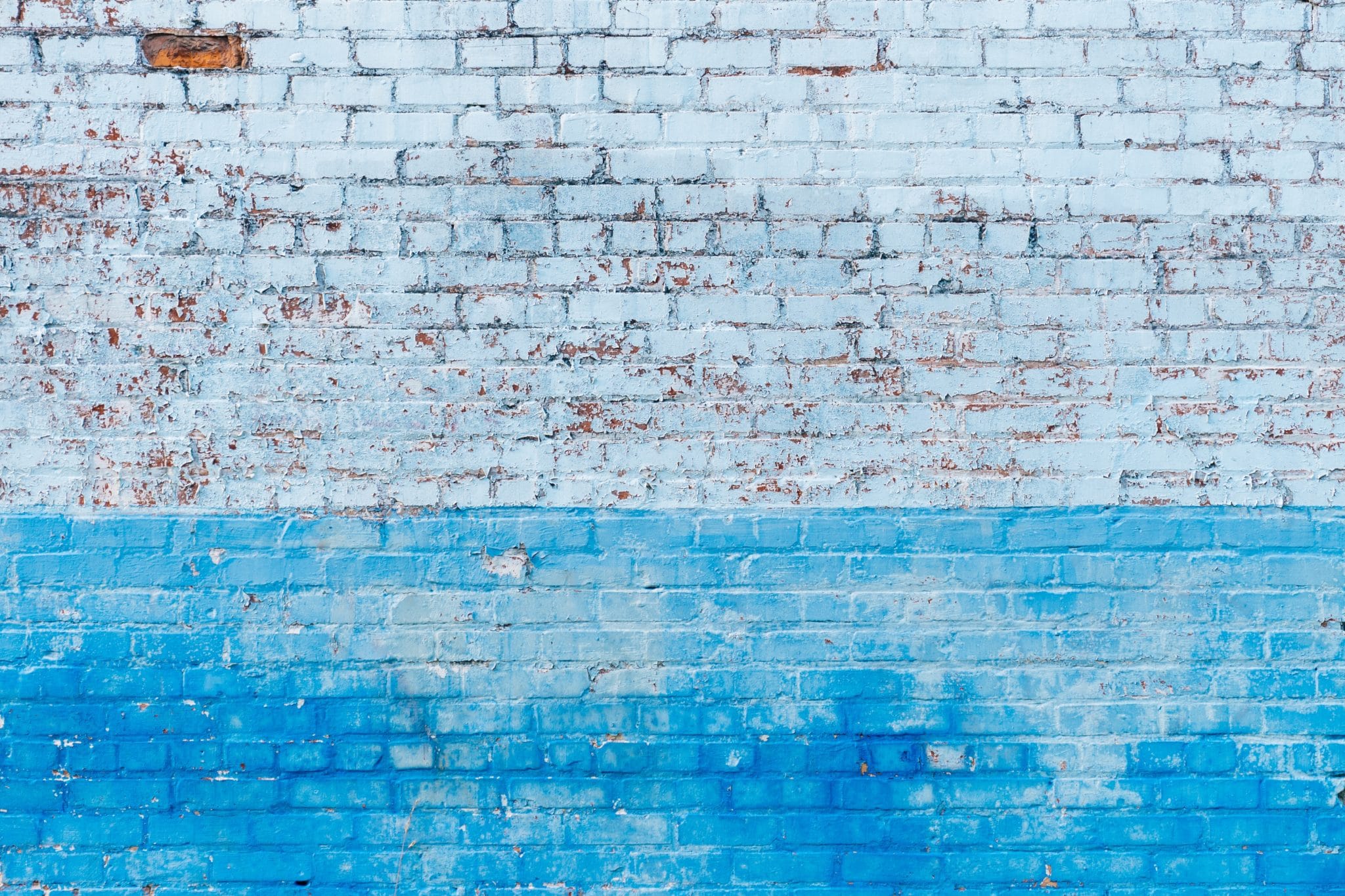 A picture of a brick wall painted half blue and half white almost likes clouds because this article is about cloud-based firewalls known as Firewalls as a Service or FWaaS.